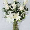 White roses and lilies arranged in a clear glass vase