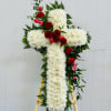 White floral cross on a wooden easel with red carnations