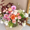 Mixed bouquet of pink, peach, orange, and white flowers in a glass vase
