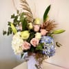 A soft collection of seasonal flowers in light blues, cream and blush