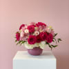 Pink and white rose bouquet in a purple vase