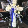 White floral standing cross with blue ribbon and yellow roses