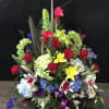 Large standing floral arrangement with red roses, lilies, and hydrangeas