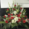 Large red and white floral arrangement in a black pedestal vase