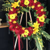 Heart-shaped floral wreath of red and yellow roses with ribbon on an easel