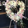 Heart-shaped floral wreath on an easel with pink and white flowers
