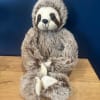 Plush sloth toy sitting on a wooden surface