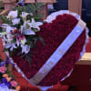 Heart-shaped red floral tribute with white lilies and a ribbon
