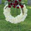 Standing funeral wreath with white flowers and red roses on an easel