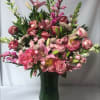 Pink mixed flower arrangement in a tall green vase