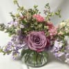 Lavender rose bouquet with pink and white flowers in a round glass vase