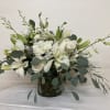 White floral arrangement in a glass vase with long green stems