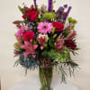 Mixed pink, purple, and green flowers arranged in a glass vase