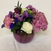 Mixed bouquet of pink, purple, and white flowers in a purple glass vase