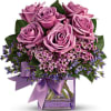 Pink roses in a clear glass vase with a purple ribbon