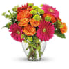 Bouquet of orange roses and pink gerbera daisies in a clear glass vase