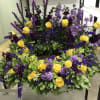 Large wreath of yellow roses and purple flowers on a stand