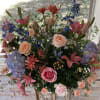Large mixed floral arrangement with roses, lilies, hydrangeas, and blue flowers