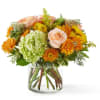 Peach roses and orange mums in a clear glass vase