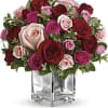 Bouquet of red, pink, and blush roses in a clear square vase
