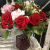 Bouquet of red roses, pink alstroemeria, and white carnations in a red vase