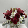 Red lilies and roses arranged in a clear glass vase with white blooms