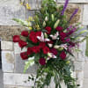 Tall standing floral spray with red roses, lilies, and purple accents