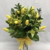 Yellow tulips arranged in a clear glass vase with a yellow ribbon