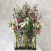 Tall floral arrangement with pink and white tulips in a clear rectangular vase