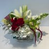Red roses and white lilies in a clear glass vase with white hydrangea
