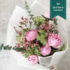 Pink peony bouquet with small filler flowers in white wrapping