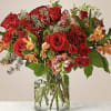 Red roses and mixed blooms arranged in a clear glass vase