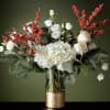 White flowers and red berry branches in a glass vase with a gold base