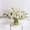 White floral arrangement in a clear glass vase on a small round table