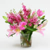 Pink lilies, tulips, and gerbera daisies in a glass vase