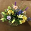 Mixed bouquet in a glass vase with lilies, roses, and blue flowers