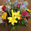Mixed bouquet of lilies, roses, and blue delphinium in a glass vase