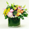 Mixed bouquet of pink lilies, yellow daisies, and roses in a glass vase