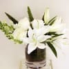 White lilies and roses arranged in a clear glass vase