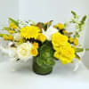 Yellow and white floral arrangement in a green glass vase