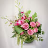 Pink roses and orchids arranged in a green vase
