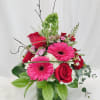 Pink gerbera daisies and red roses arranged in a glass vase