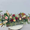 Long floral centerpiece with red and peach roses in a rectangular container