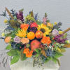 Colorful fruit and flower arrangement in a white vase