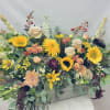 Large mixed flower arrangement with sunflowers, roses, and daisies in a rectangular container