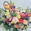 Mixed bouquet of roses, snapdragons, and chrysanthemums in a white vase