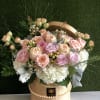 Round hatbox arrangement of pastel roses and white hydrangeas accented with pearls and filler blooms.