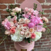 Pink and white flower arrangement with roses and peonies in a pink hatbox