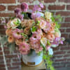 Round hatbox arrangement of peach roses and pink lisianthus with trailing greenery