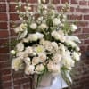 Large white and cream flower arrangement with roses and dahlias in a white ceramic vase